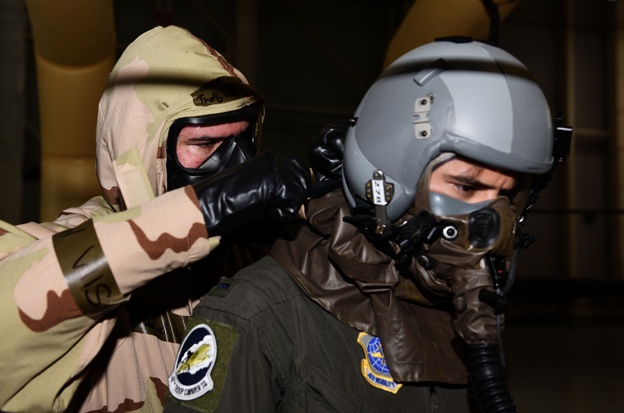 Staff Sgt. Timothy Wochnick, 317th Operations Support Squadron, aircrew flight equipment, assists 1st Lt. Garrett Iapicco, 40th Airlift Squadron, co-pilot through the decontamination line