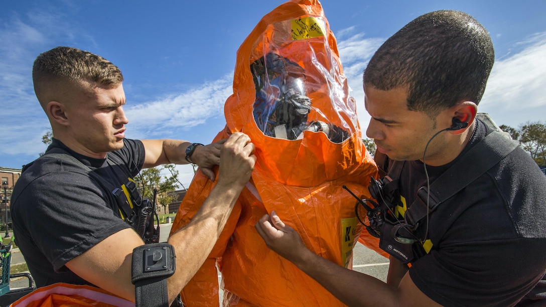 Two soldiers seal a protective suit of a third soldier.