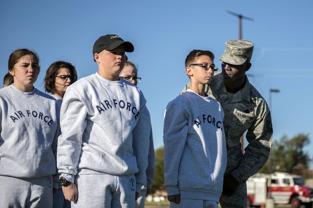 An airman gets in the face of a teenager standing in a formation with other teens, all wearing Air Force sweatsuits.