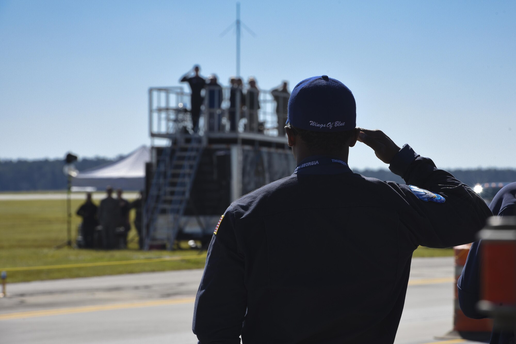 A member of the United States Air Force Academy Wings of Blue team renders a salute during the national anthem prior to the kick off of the Thunder Over South Georgia Air Show, Oct. 29, 2017, at Moody Air Force Base, Ga. Air shows aim to educate the public on past and present Air Force aerial capabilities, increase recruiting and show appreciation to the local community. (U.S. Air Force photo by Senior Airman Greg Nash)