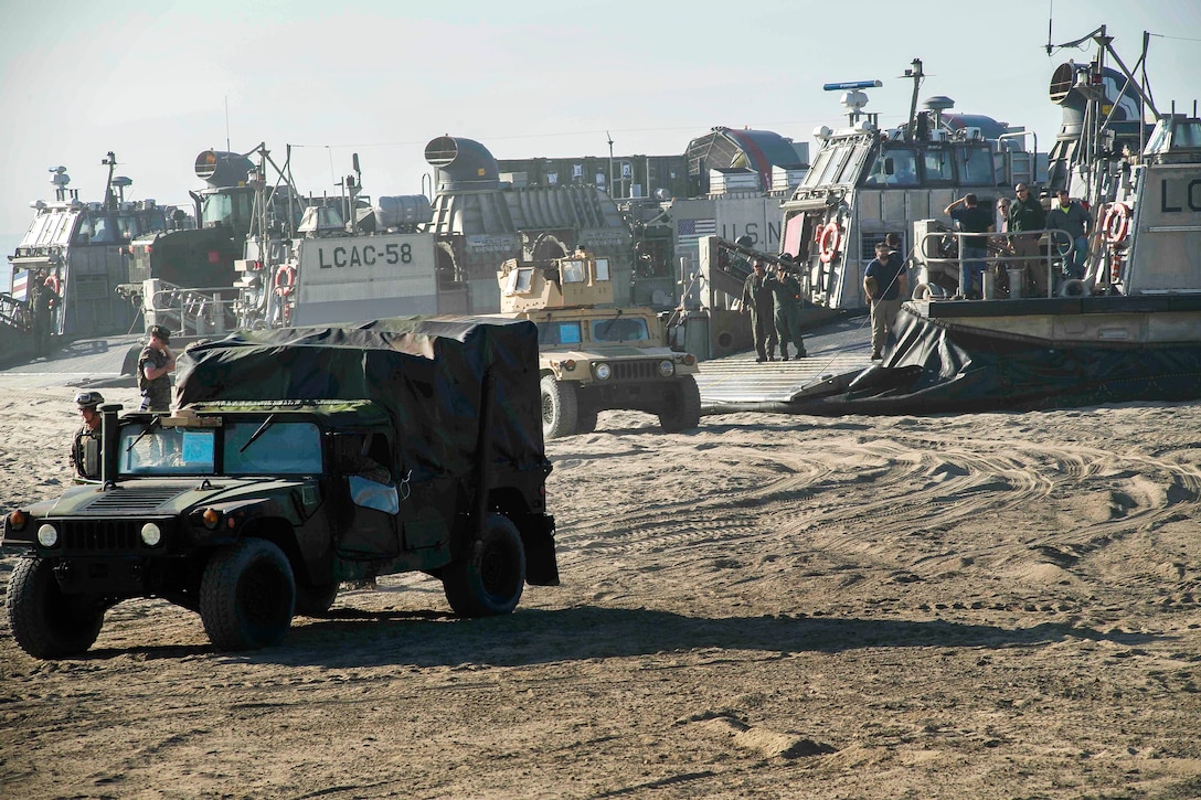 Humvees drive away from air-cushion landing craft on Red Beach during bilateral exercise Dawn Blitz 2017.