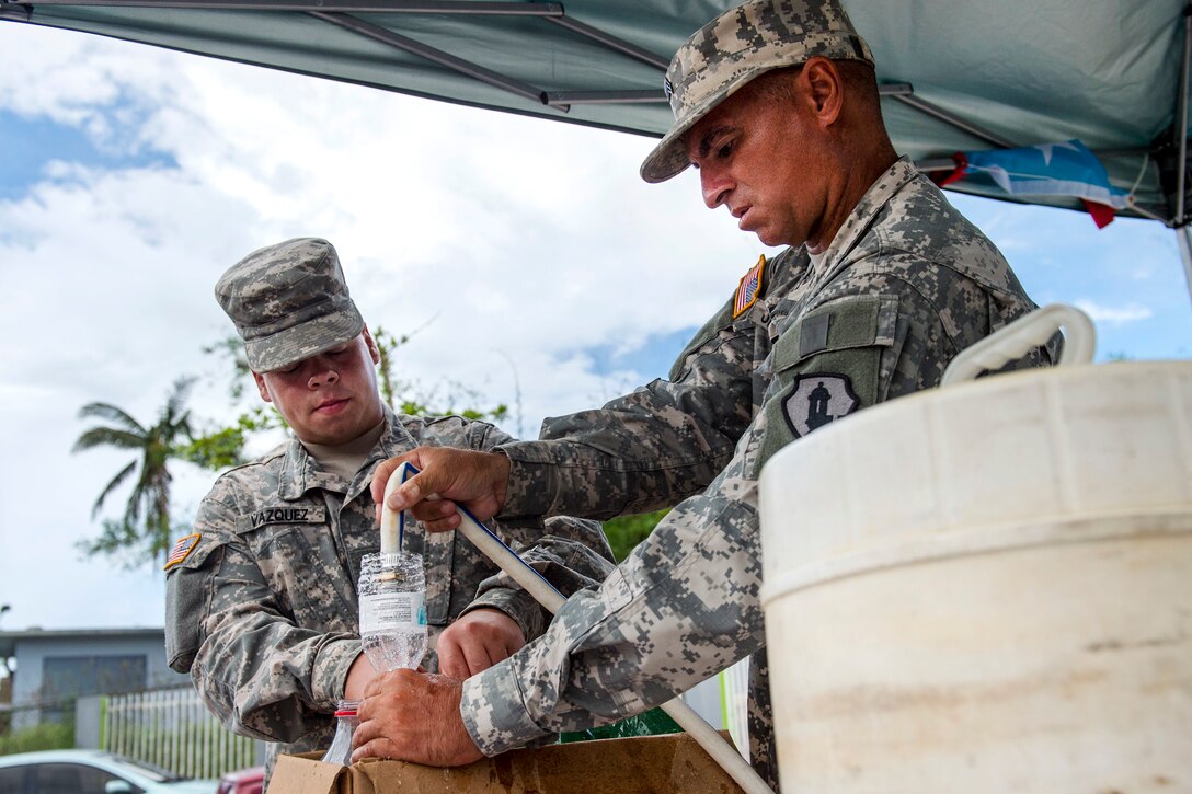 Army Sgt. Hector Jimenez, right, and Army Pvt. Julian Vazquez prepare to distribute clean water.