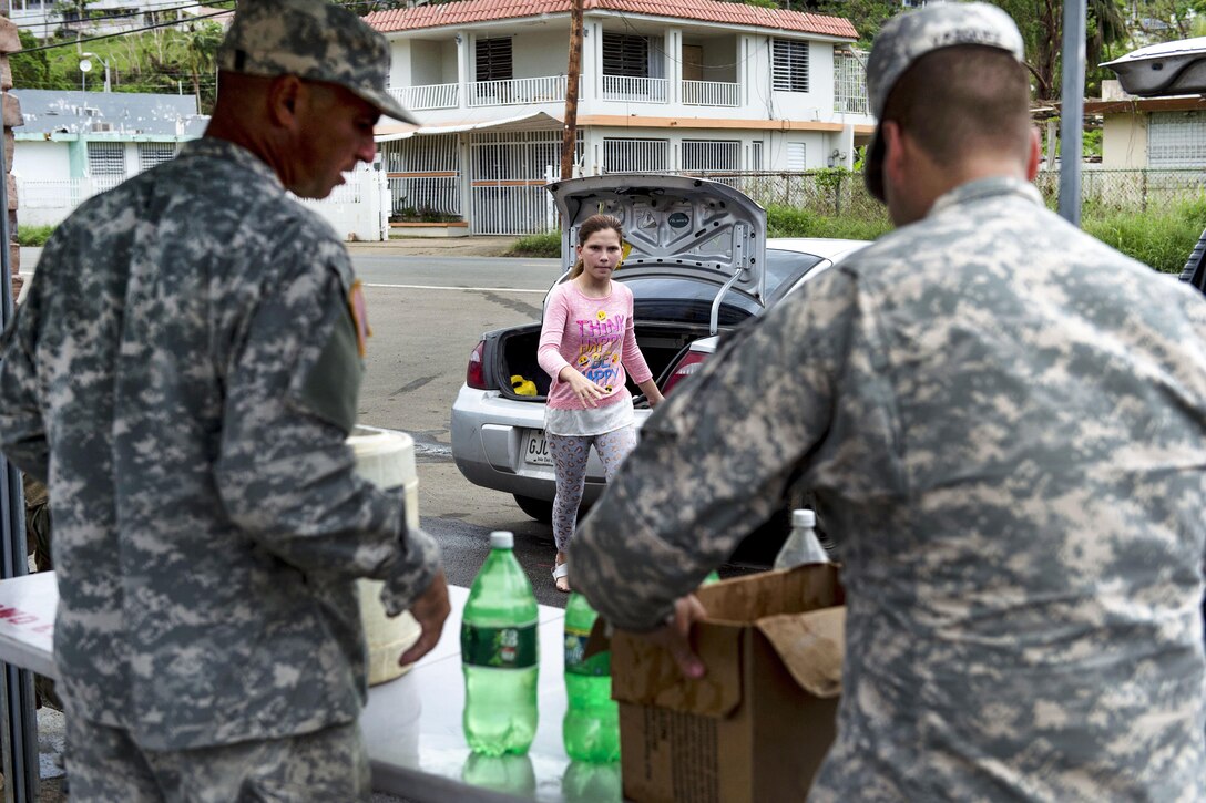 Army Sgt. Hector Jimenez, left, and Army Pvt. Julian Vazquez distribute clean water in Campo Rico.