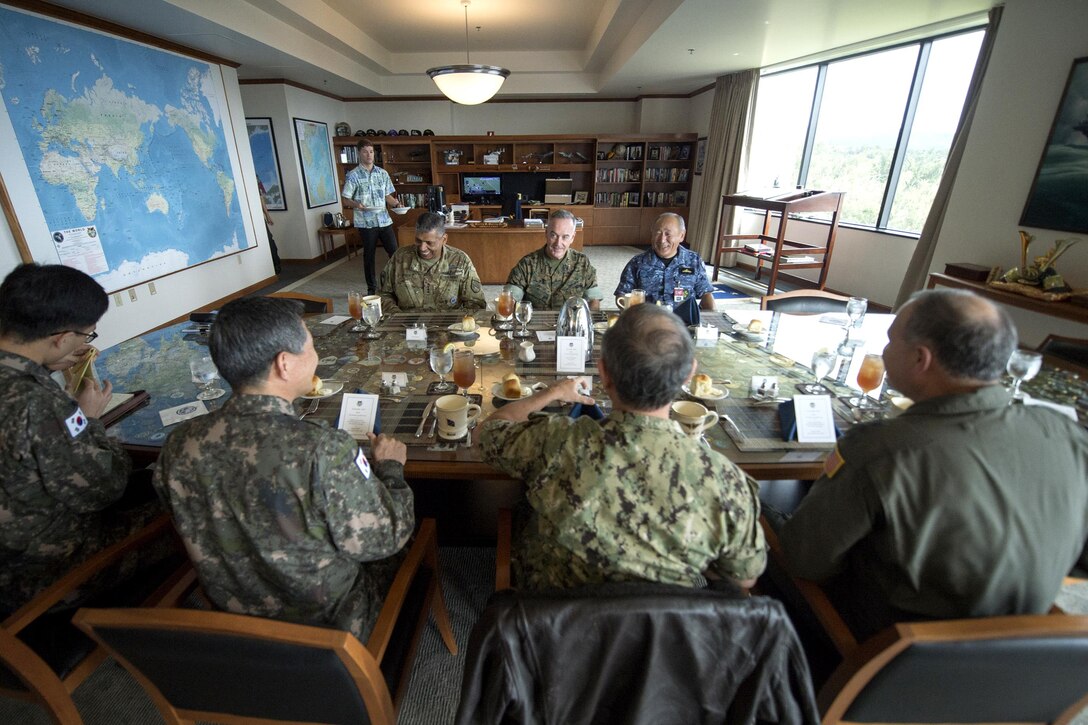 A group of senior military officials from the U.S., South Korea and Japan sit at a table.