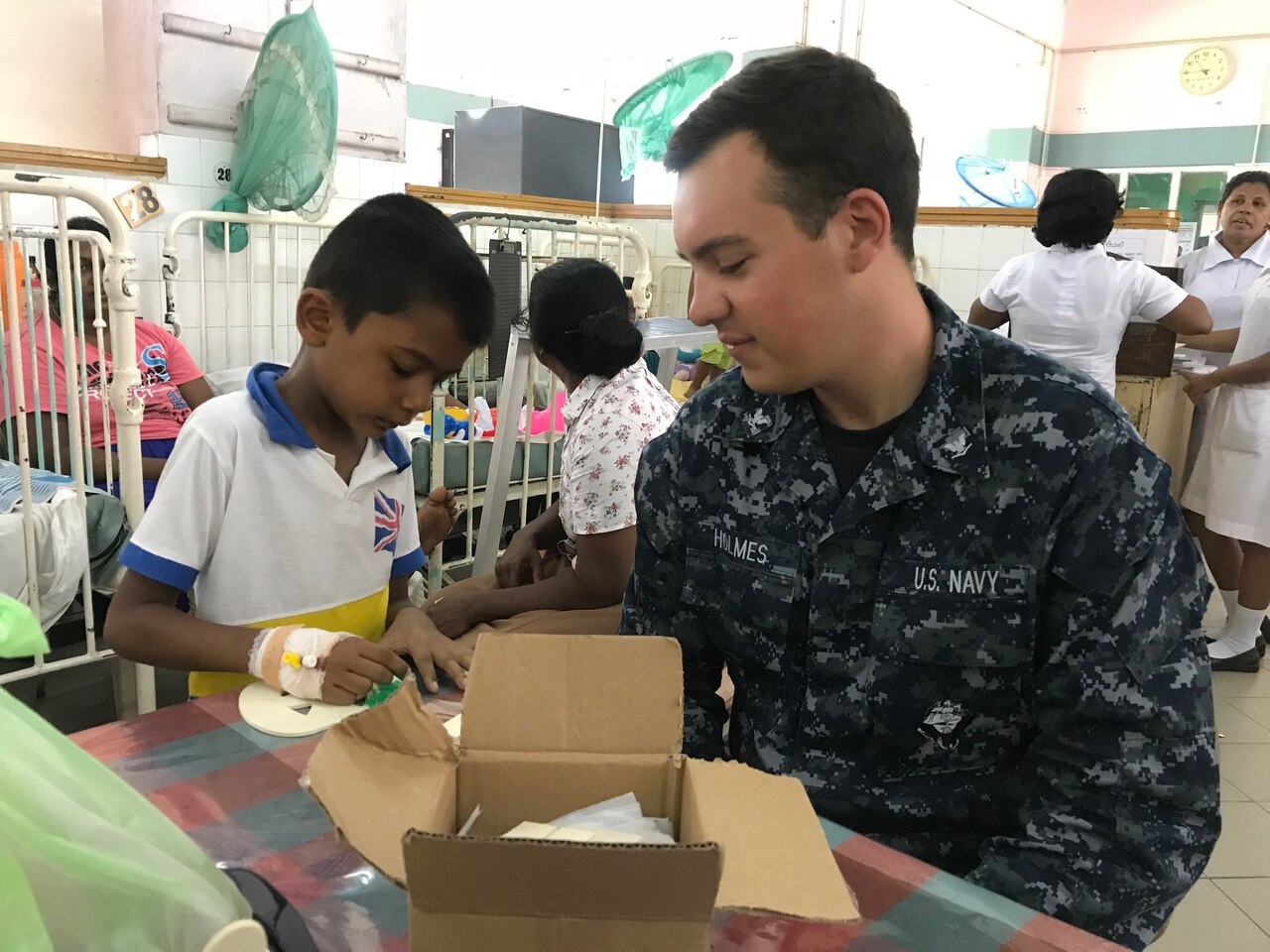 U.S. sailor helps Sri Lankan child with craft project.