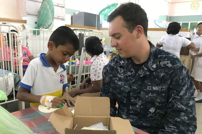 A sailor sits and talks to a child.