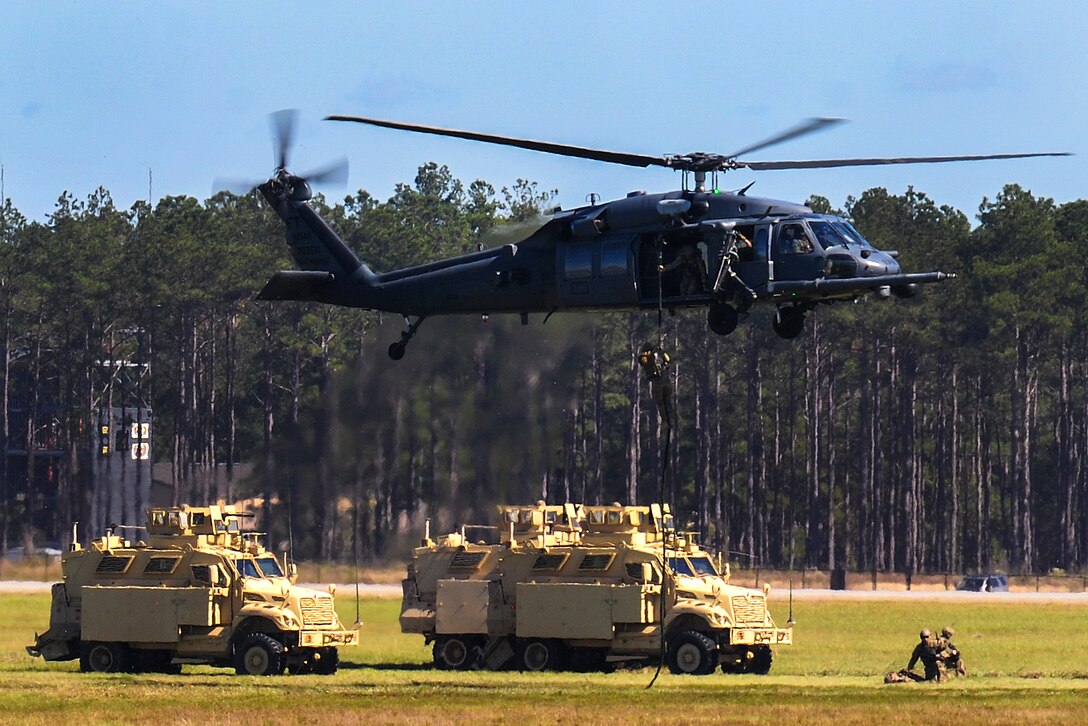 An Air Force aerial team demonstrates rescue rappelling from an HH-60G Pave Hawk helicopter.