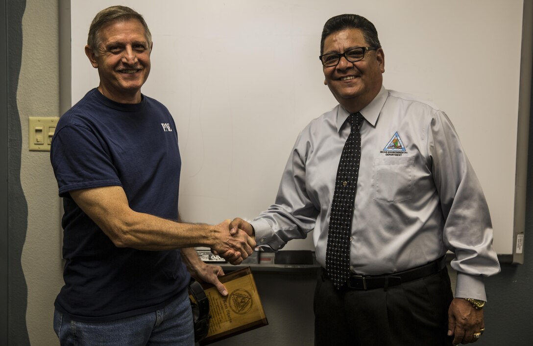 David Rodriguez, the director of Marine Corps Air Station Yuma, Ariz., Environmental Department, congratulates Kenneth Starts, the environmental compliance coordinator with VMFT-401, for his superior performance of duties, Tuesday, April 18, 2017. Starts manages 46 designated waste streams, 746 items of hazardous material and consistently receives outstanding marks with no discrepancies on his Annual Environmental Compliance Inspections.