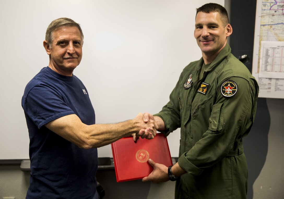 U.S. Marine Corps Lt. Col. Jayson Tiger, the commanding officer of Marine Fighter Training Squadron 401, congratulates Kenneth Starts, the environmental compliance coordinator with VMFT-401, for his superior performance of duties at Marine Corps Air Station Yuma, Ariz., Tuesday, April 18, 2017. Starts manages 46 designated waste streams, 746 items of hazardous material and consistently receives outstanding marks with no discrepancies on his Annual Environmental Compliance Inspections.
