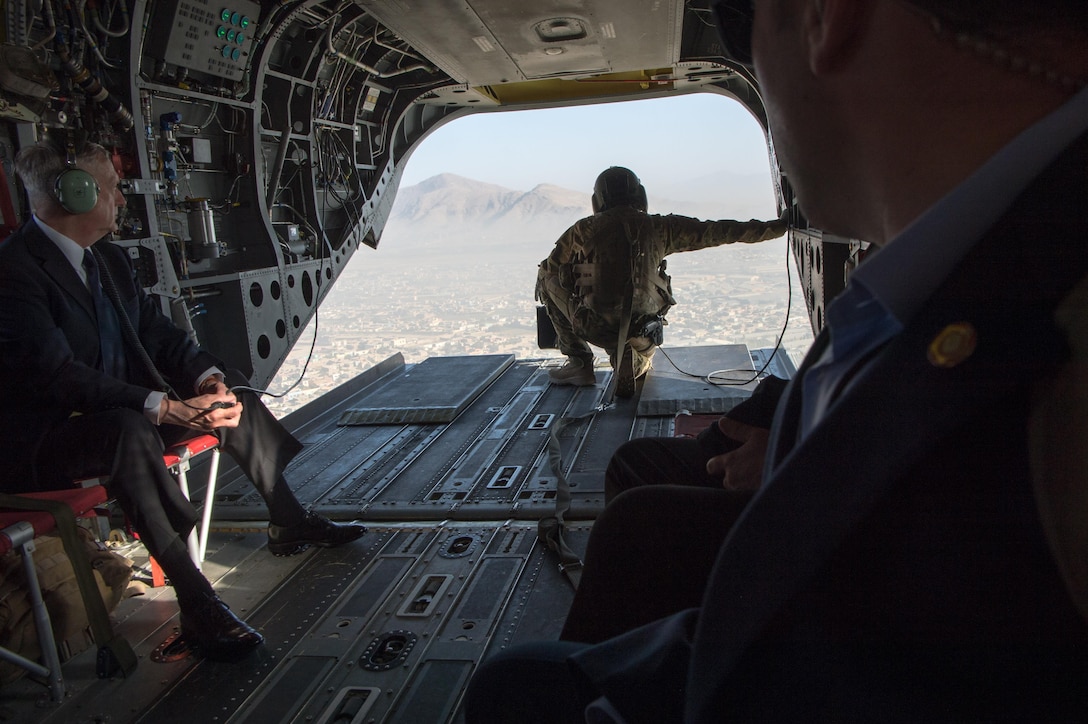 Defense Secretary Jim Mattis and a soldier look out of the tailgate of a CH-47 Chinook helicopter over Afghanistan.