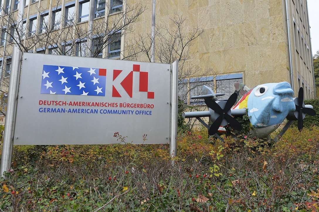 The German-American Community Office Sign stands outside the office's building next to a statue of a fish with wings at Kaiserslautern, Germany, Oct. 26, 2017. GACO serves as a link between the German and American populations in the Kaiserslautern Military Community. (U.S. Air Force photo by Airman 1st Class Joshua Magbanua)