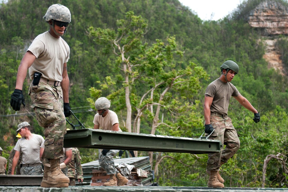 Guardsmen carry a section of a 40-foot bridge they are building for the citizens of Guajataca