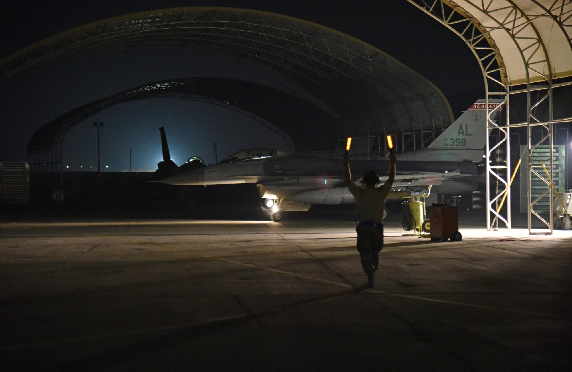 A crewmember guides an F-16 Fighting Falcon pilot into an overhang at the 407th Air Expeditionary Group in Southwest Asia Oct. 29. After the mission, this F-16 accomplished 8,000 flying hours. (U.S. Air Force photo by Staff Sgt. Joshua Edwards/Released)