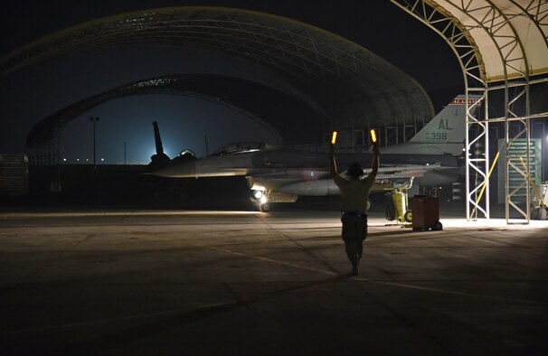 A crewmember guides an F-16 Fighting Falcon pilot into an overhang at the 407th Air Expeditionary Group in Southwest Asia Oct. 29. After the mission, this F-16 accomplished 8,000 flying hours. (U.S. Air Force photo by Staff Sgt. Joshua Edwards/Released)