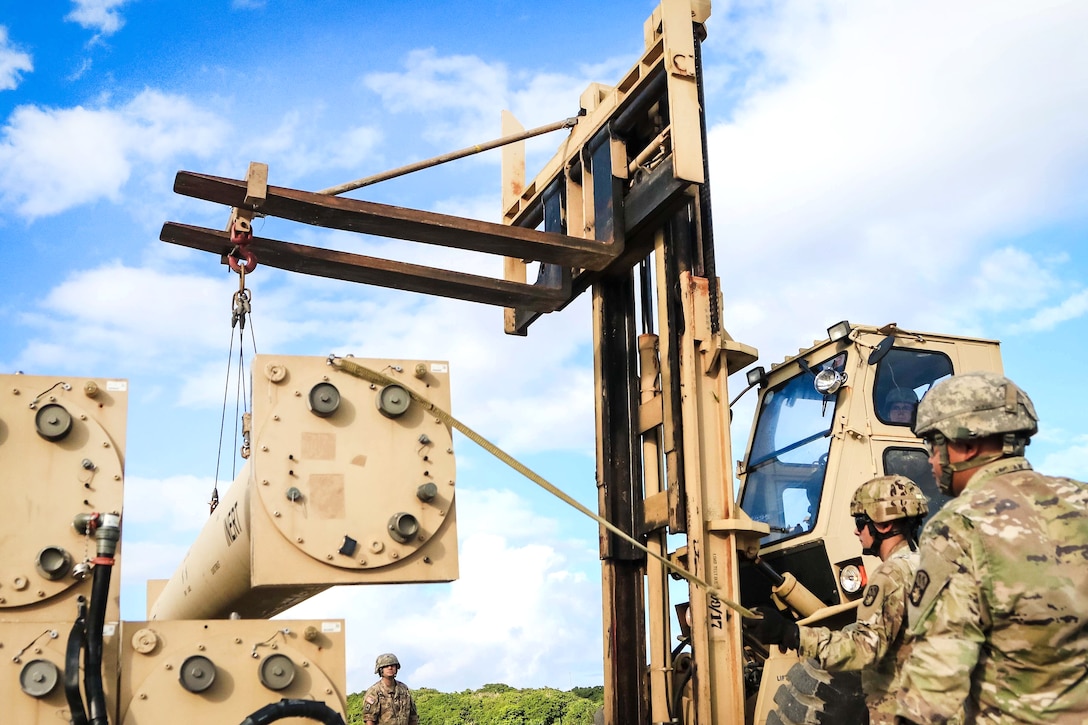 Soldiers work together to lift a missile round trainer on a Terminal High Altitude Area Defense weapon system.