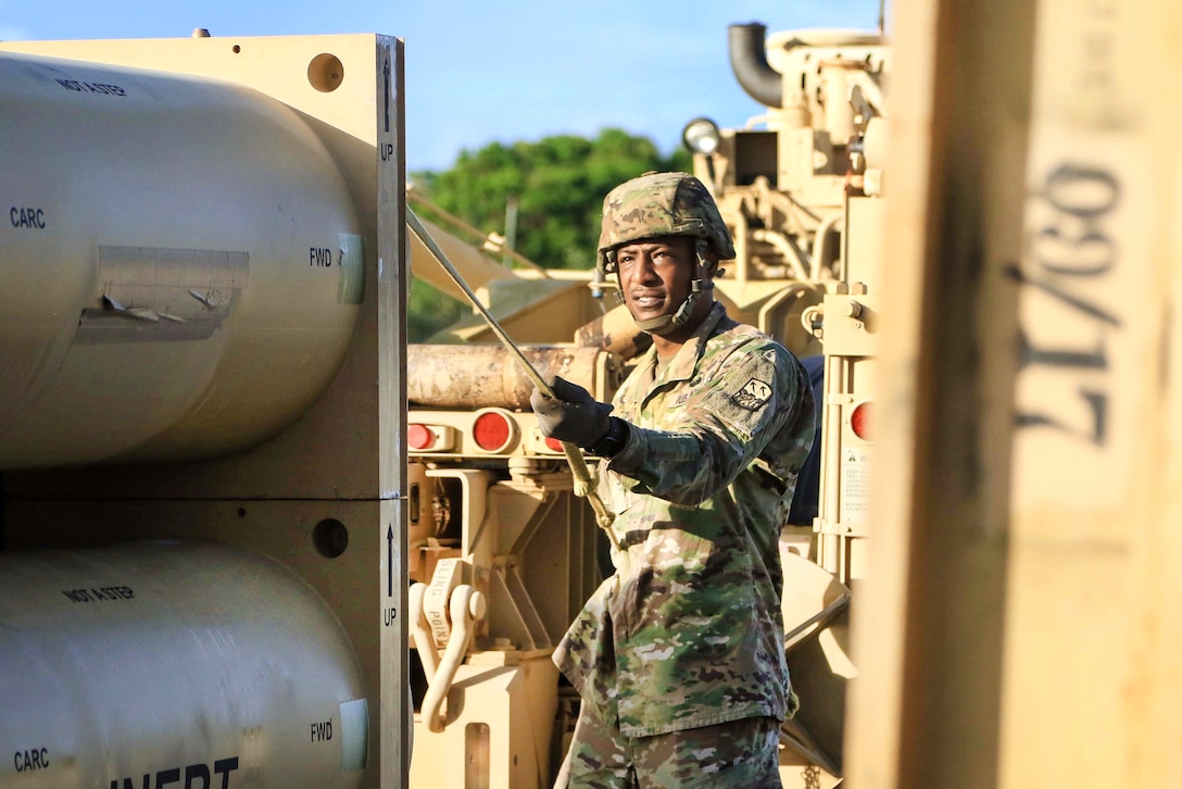 A soldier prepares to offload a missile round trainer on a weapon system.