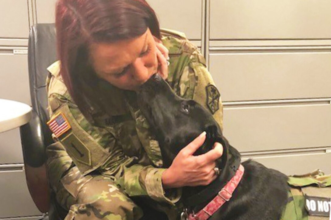 Army Master Sgt. Leigh Michel gets a kiss from her service dog Lizzy.