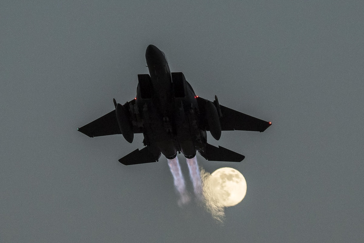 An aircraft takes off with a full moon in the sky.