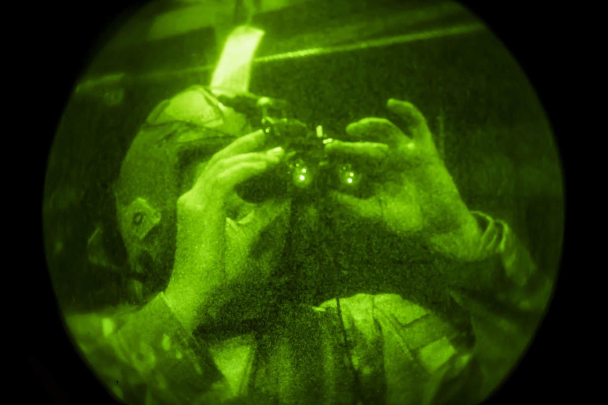 Airman looks through night vision goggles.