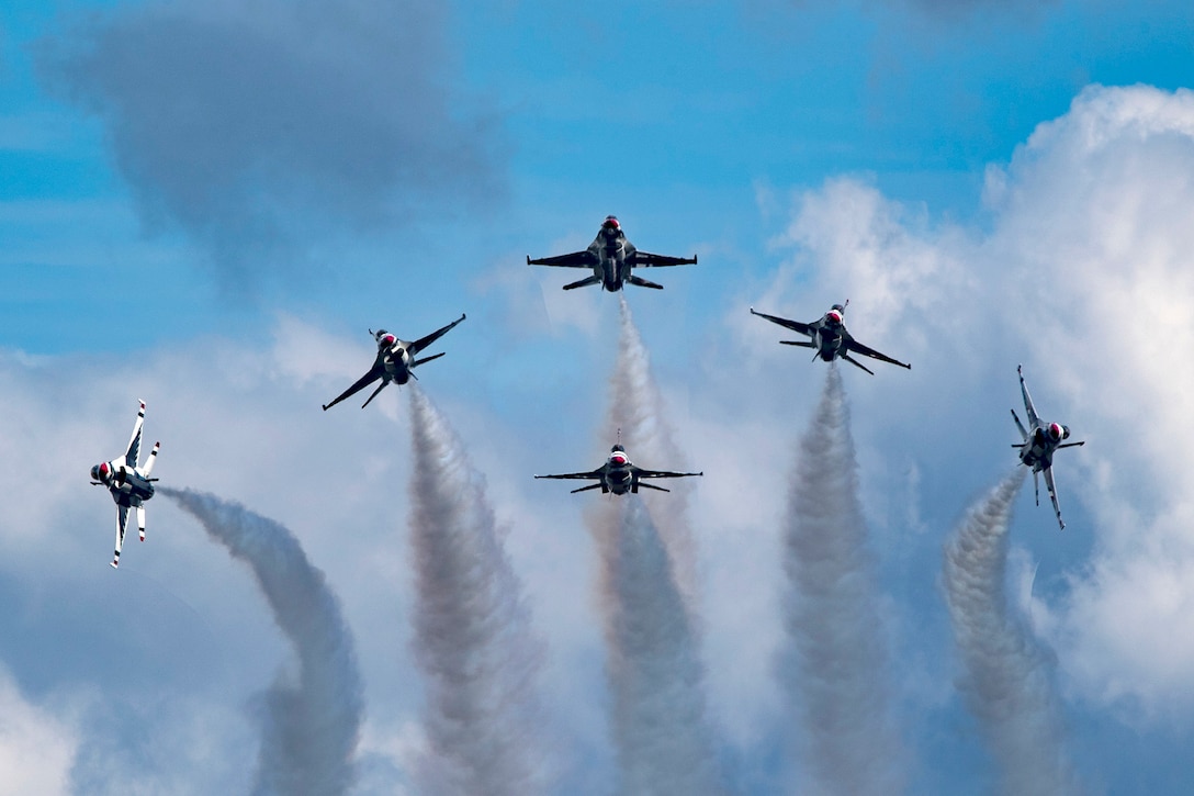 Six fighter jets fly in a pattern through the sky.