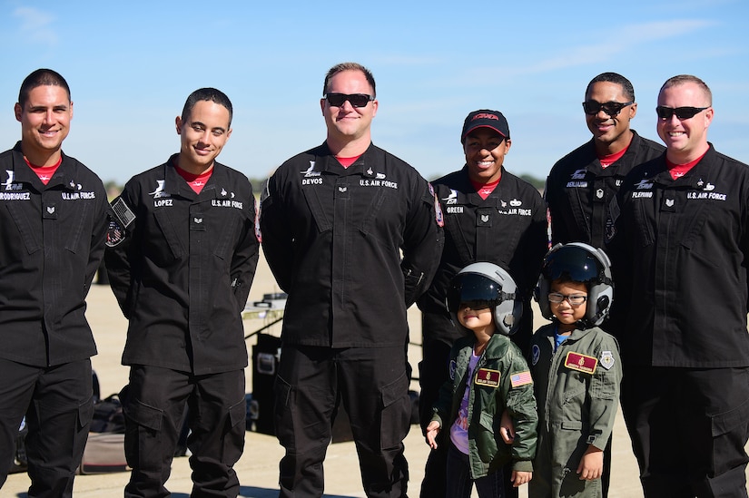 F-22 Raptor Demonstration Team members posing for a photo with two children dressed in flight suits.