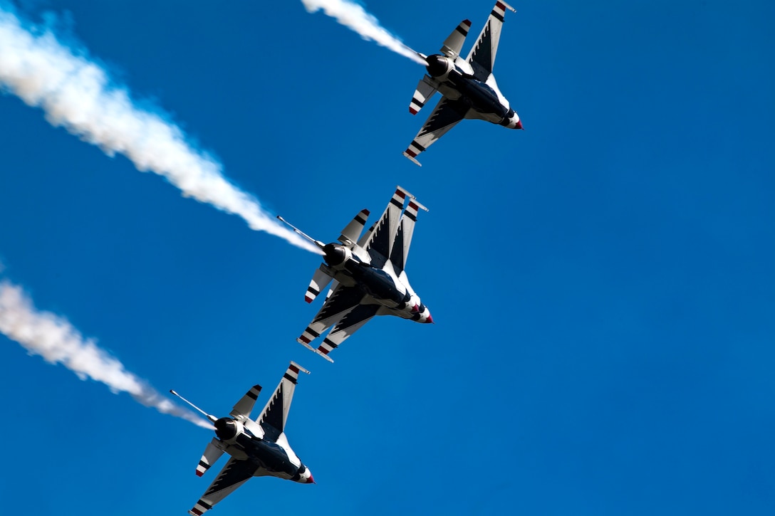 Three fighter jets fly across a blue sky.