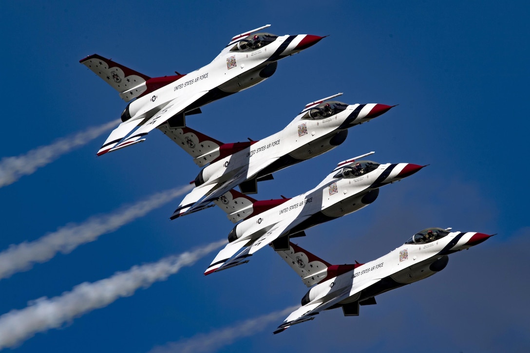 Four fighter jets fly across a blue sky.