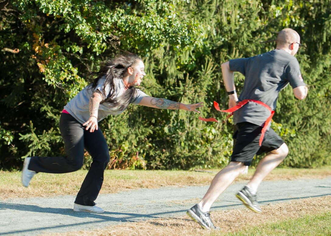 Spc. Brooke Bristow, Armed Forces Medical Examiner System mortuary affairs specialist, chases a runner during the 2017 Zombie Fun Run Oct. 27, 2017, at Dover Air Force Base, Del.