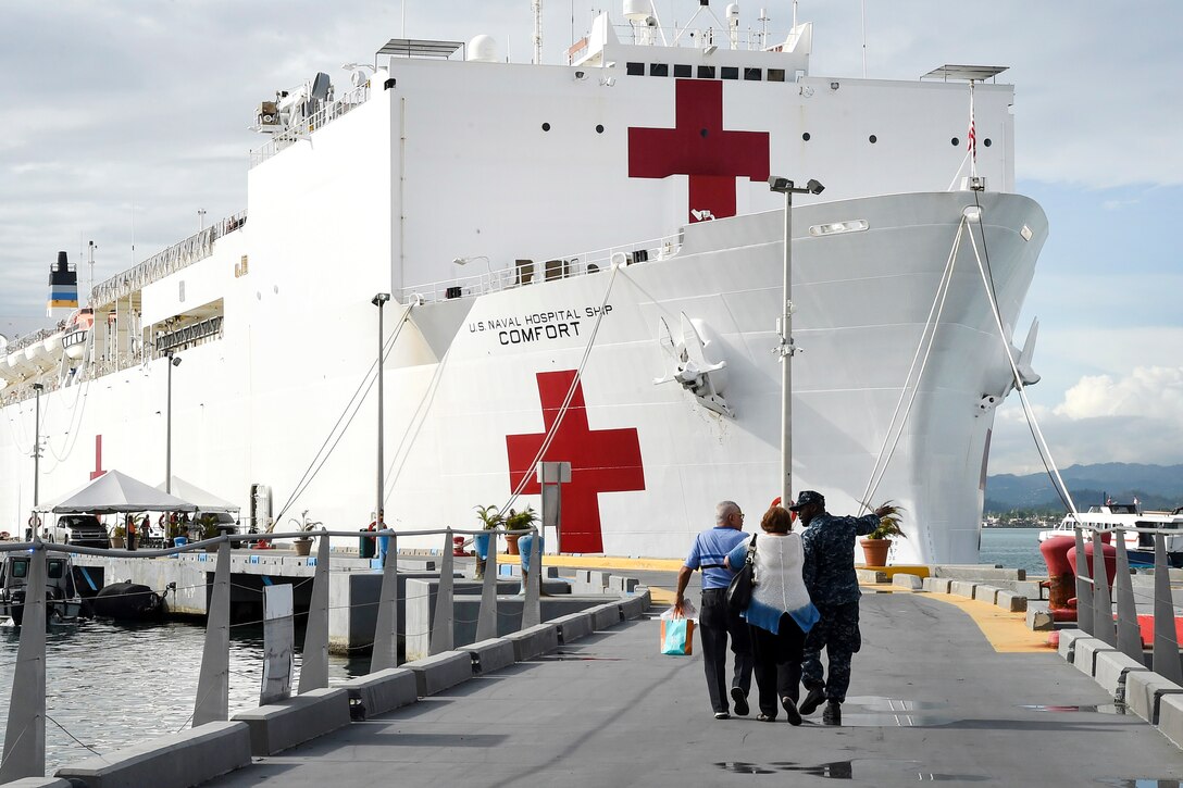 A sailor escorts patients to the hospital ship USNS Comfort.