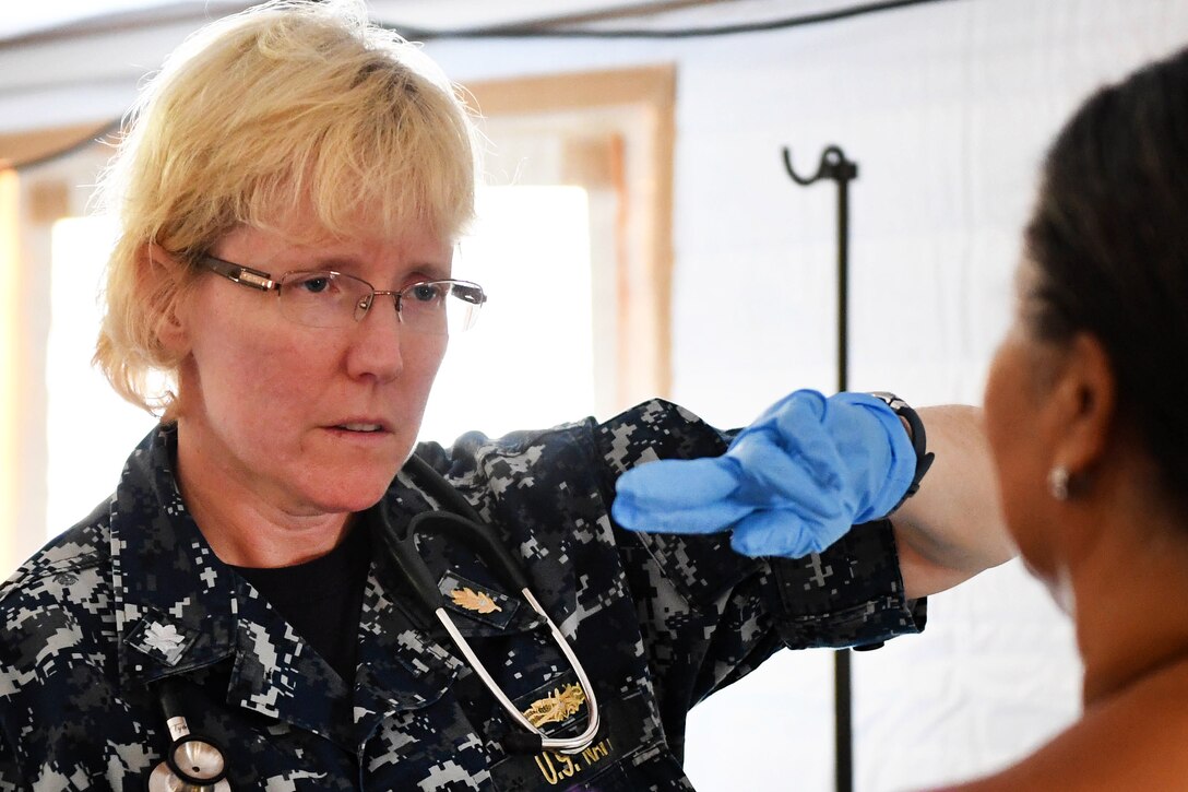 A Navy commander checks a patient's eyesight.