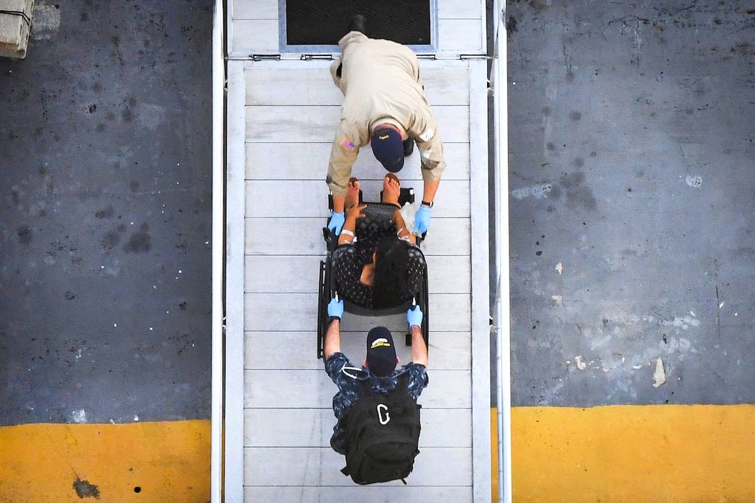 A patient in a wheelchair is wheeled along a pier.