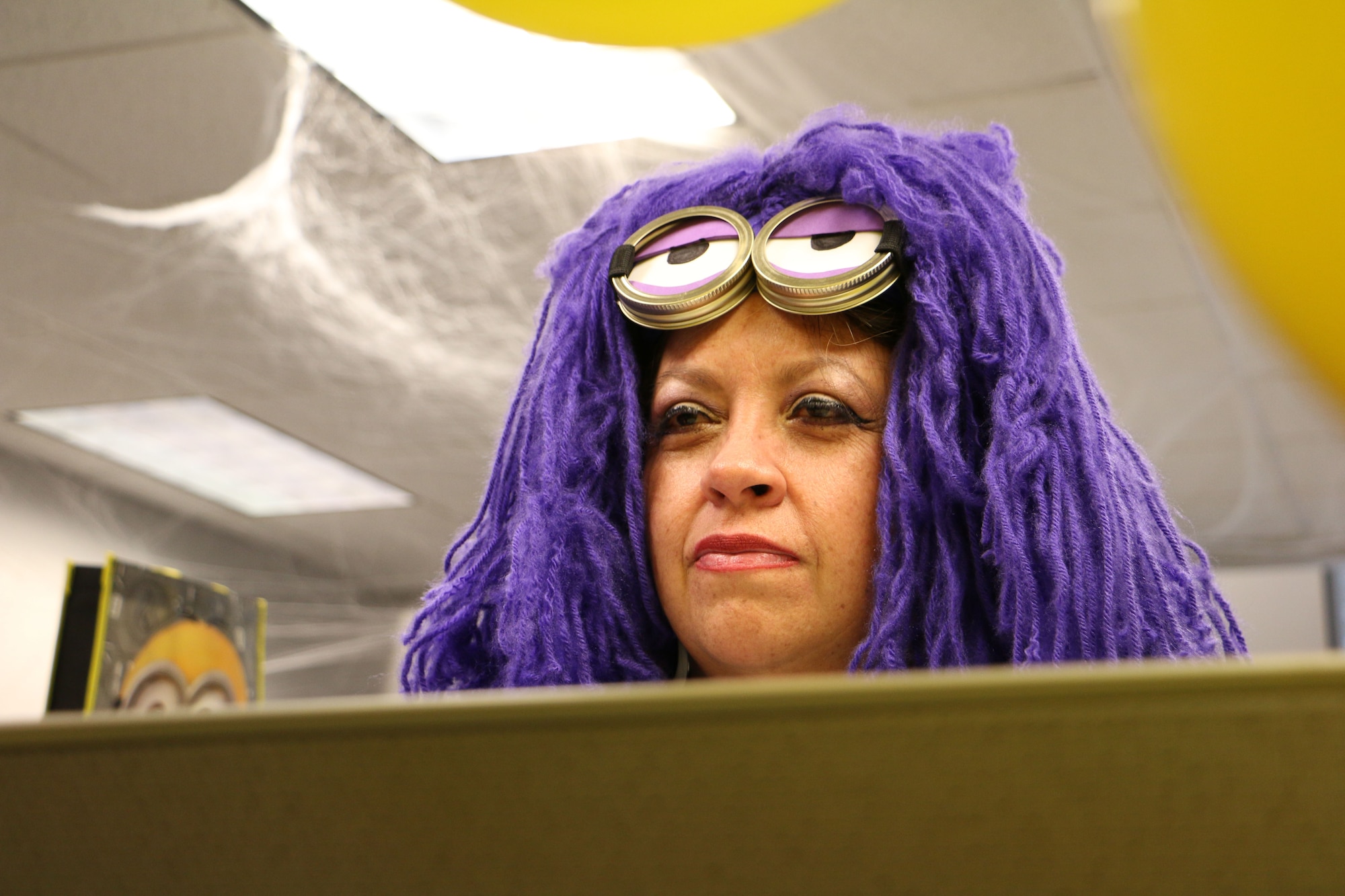 Gina Garcia, 21st Contracting Squadron contracting specialist, peers over her cubicle while dressed as a purple minion from the movie series "Despicable Me" at Peterson Air Force Base, Colorado, Oct. 31, 2017. Some units on Peterson AFB dressed in costume to celebrate Halloween. (U.S. Air Force photo by Staff Sgt. Erica Picariello)