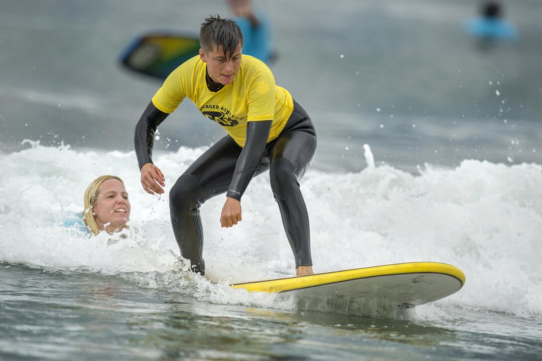 A surfer catches a wave with the help of an instructor.