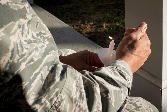 Col. Jimmy Canlas, 437th Airlift Wing commander, holds a lit candle during a moment of silence remembering all of those affected by domestic violence during a ceremony at Joint Base Charleston, S.C., Oct. 30, 2017.
