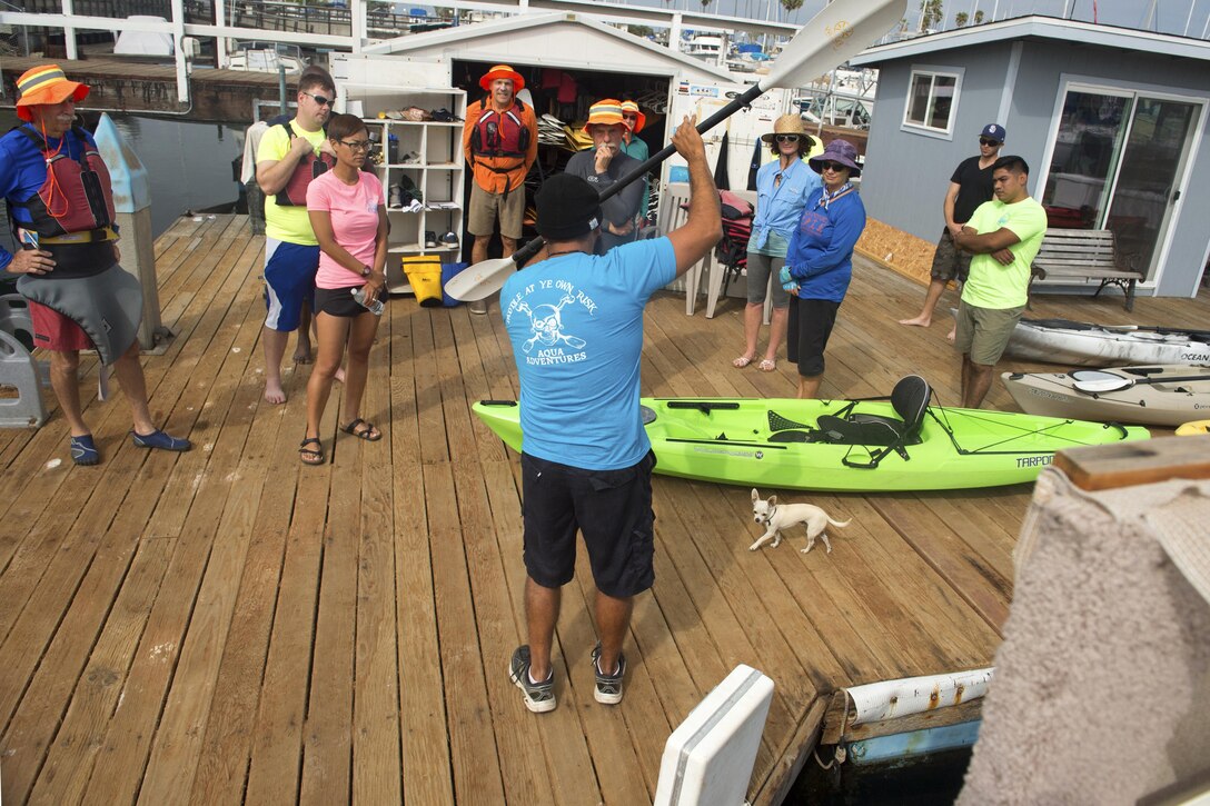 An instructor demonstrates paddling techniques for a group of kayakers.