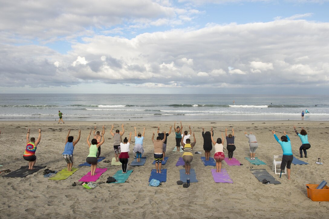 A group pf poeple practice yoga on a beach.