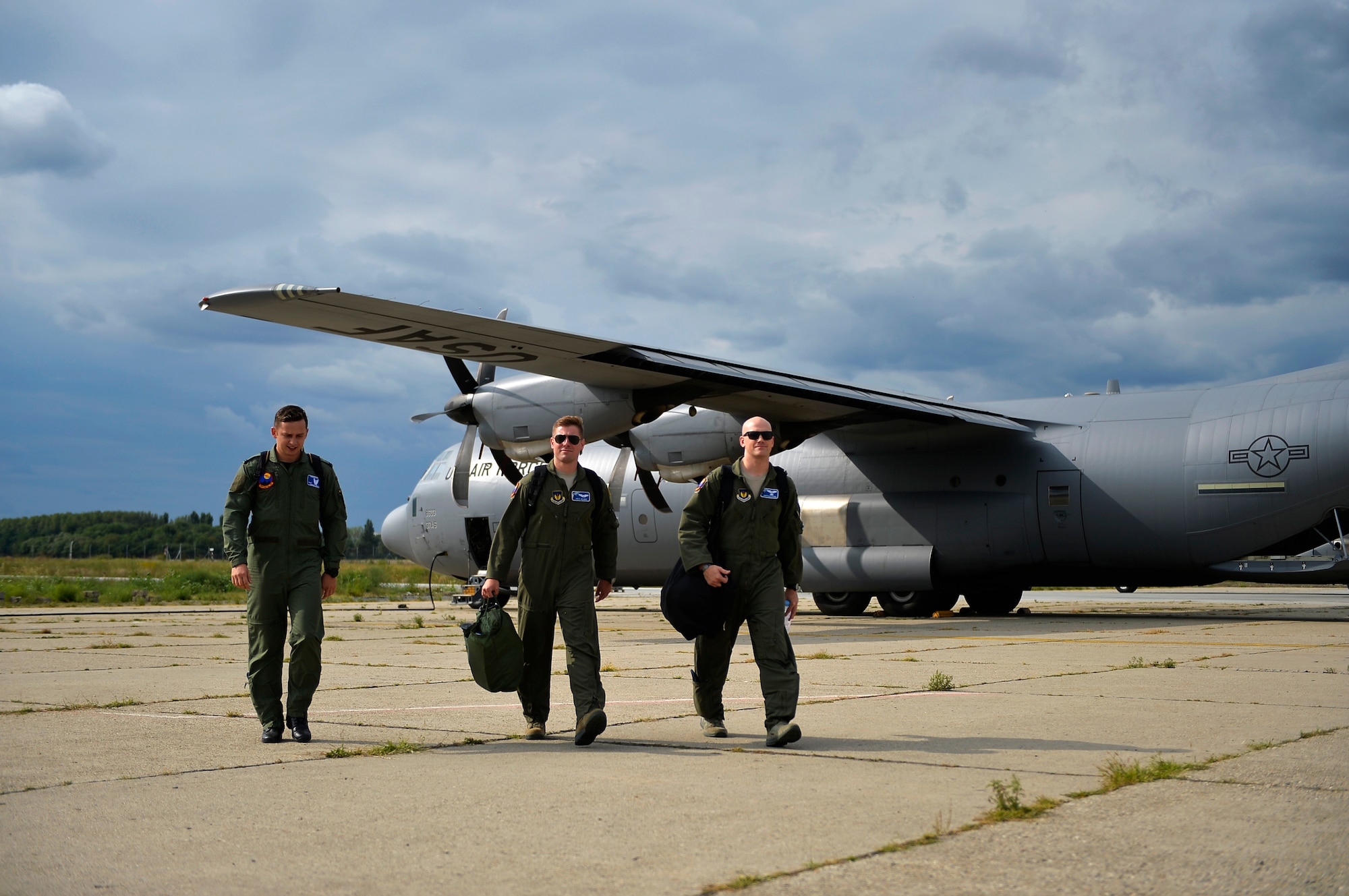 U.S. Air Force C-130J pilots from the 37th Airlift Squadron, (right and center), along with one Romanian Air Force pilot, walk back to their units after conducting a training flight at Otopeni Air Base, Romania, Aug. 29, 2017.