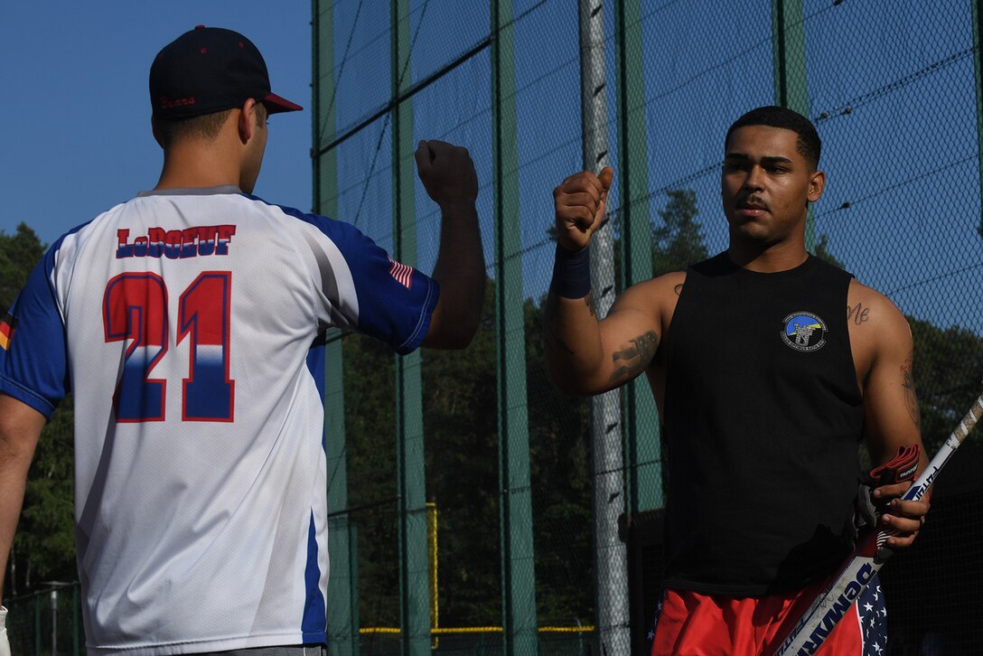 U.S. Air Force Airman 1st Class Kristopher Cooper, 86th Maintenance Squadron sheet metal technician, bumps fists with a teammate to celebrate a good inning during an intramural softball game on Ramstein Air Base, Germany, Aug 22, 2017. Cooper’s team went on to win the championship game, ending their season with 10 wins and two losses. (U.S. Air Force photo by Staff Sgt. Nesha Humes Stanton)