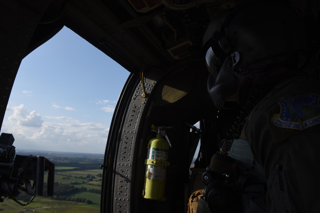 An Airman assigned to the 56th Rescue Squadron scans the horizon while flying in an HH-60G Pave Hawk over Royal Air Force Lakenheath, England, Aug. 31. The Pave Hawks of the 56th RQS provide RAF Lakenheath with day or night personnel recovery capabilities. (U.S. Air Force photo/Airman 1st Class Eli Chevalier)