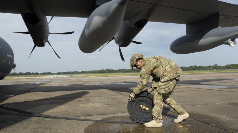 U. S. Air Force Staff Sgt. John San Inocencio, 23d Logistics Readiness Squadron, rolls a fuel line toward a HC-130J Combat King II Aug. 31, 2017, following a hot refuel of a MH-60S Seahawk at Jack Brooks Regional Airport in Beaumont, Texas.