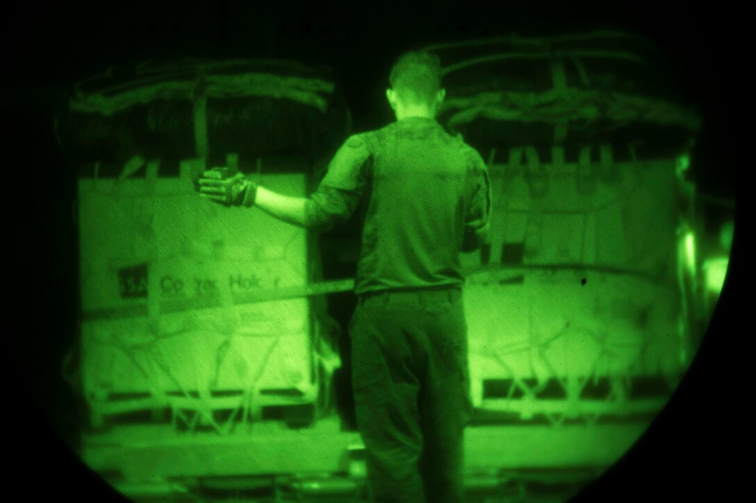 As seen through a night-vision device, Air Force Senior Airman Tom Saunders directs a k-loader with pallets
