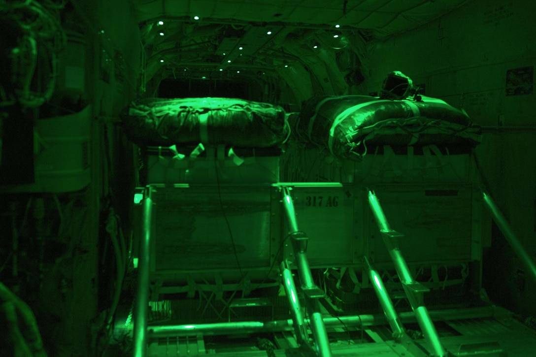 As seen through a night-vision device, pallets of cargo and supplies sit inside a C-130J Super Hercules as they are prepped for an airdrop mission