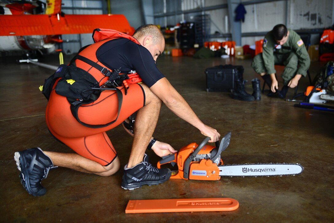 A Coast Guardsman starts a chainsaw on the floor of a command center.