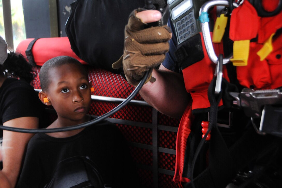 A child looks up at a guardsman while in a helicopter.