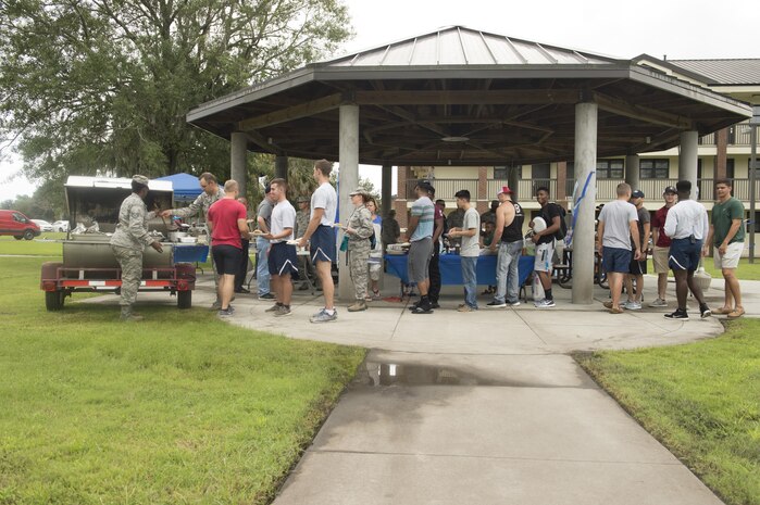 Airmen line up to be served during a dinner for dormitory residents hosted by The First Sergeants Council and Joint Base Charleston Chaplains Office in the courtyard outside the dorms Aug. 30, 2017.