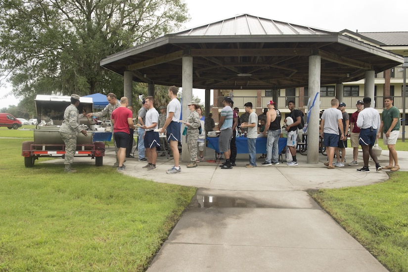 Airmen line up to be served during a dinner for dormitory residents hosted by The First Sergeants Council and Joint Base Charleston Chaplains Office in the courtyard outside the dorms Aug. 30, 2017.