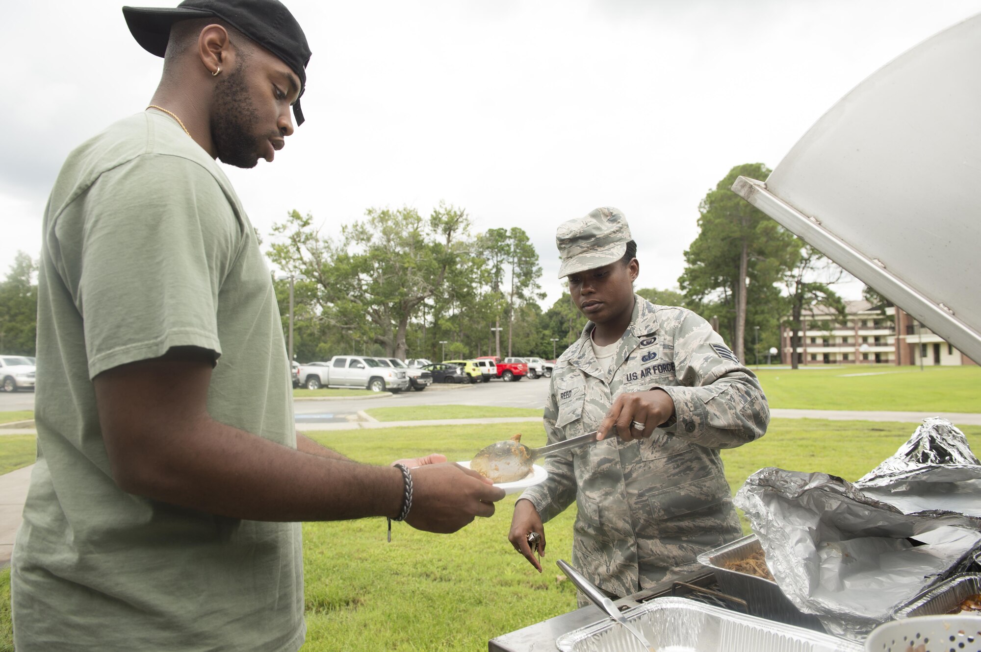 Staff Sgt. Torri Reed, right, 628th Air Base Wing chaplain assistant, serves food to Airman 1st Class Jakorey Johnson, left, 437th Maintenance Squadron crew chief, during a dinner for dormitory residents hosted by The First Sergeants Council and Joint Base Charleston Chaplains Office in the courtyard outside the dorms Aug. 30, 2017.