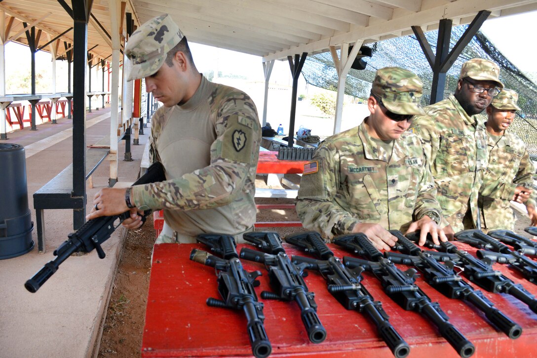 Soldiers inspect a row of shotguns prior to use.