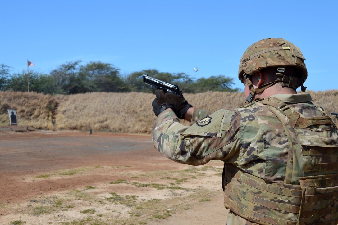 A soldier fires a handgun toward a target.