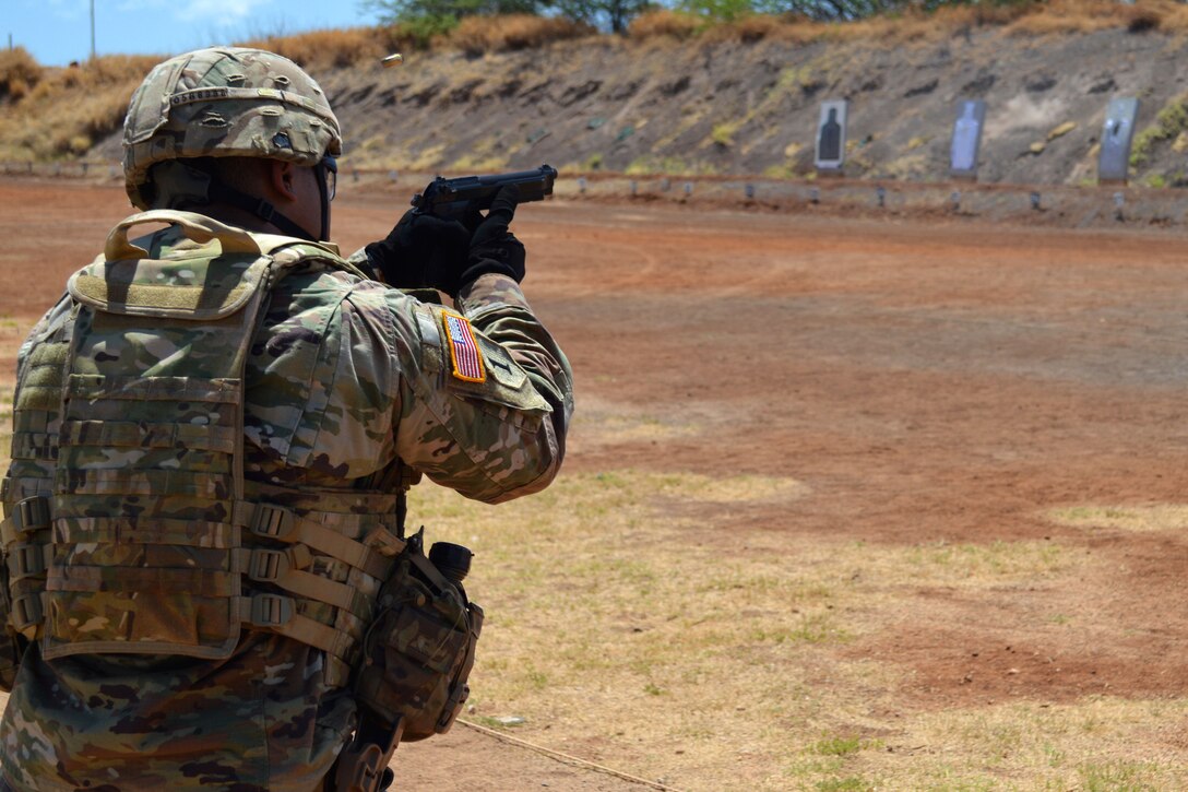 A soldier fires a pistol at a target.